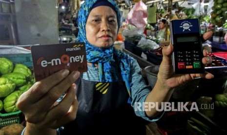 Pedagang menunjukkan kartu e-money dan mesin Q Cash saat peluncuran implementasi pembayaran non tunai di Pasar Mayestik, Jakarta, Rabu (4/4).