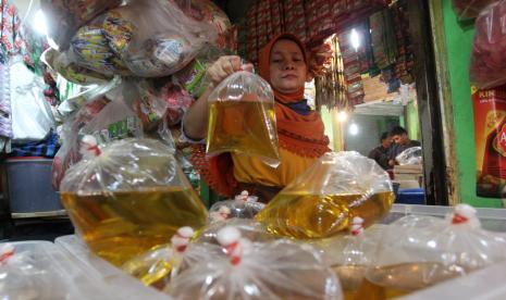 Pedagang menyusun minyak goreng curah yang telah dibungkus di pasar raya. 