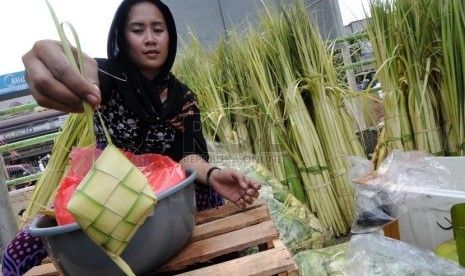   Pedagang musiman merangkai janur kelapa menjadi ketupat untuk dijual di Jalan Raya Bogor, Jakarta, Senin (14/10).  (Republika/Aditya Pradana Putra)