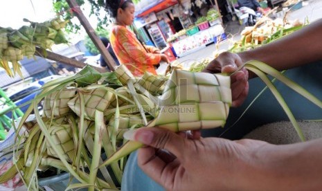   Pedagang musiman merangkai janur kelapa menjadi ketupat untuk dijual di Jalan Raya Bogor, Jakarta, Senin (14/10).  (Republika/Aditya Pradana Putra)