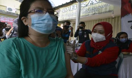 Pedagang Pasar Bambu Kuning (kiri) mengikuti vaksinasi COVID-19 dosis ketiga di Bandar Lampung, Lampung, Selasa (8/2/2022). Pemerintah Kota Bandar Lampung terus melaksanakan vaksinasi COVID-19 penguat atau booster dengan menyasar pedagang pasar di Bandar Lampung sebagai upaya pencegahan penyebaran COVID-19 khususnya varian Omicron.