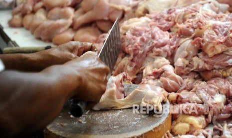 Pedagang sedang melanyani pembelian ayam potong.