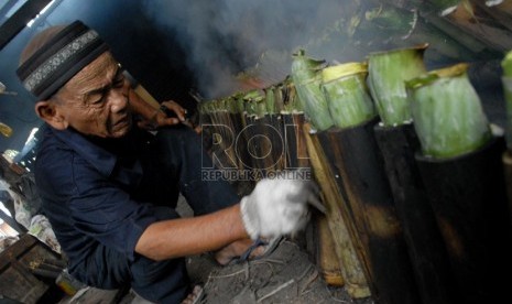  Pedagang tengah memasak Lemang menggunakan kayu bakar di kawasan Kramat, Senen, Jakarta Pusat, Selasa (23/7).    (Republika/Rakhmawaty La'lang)