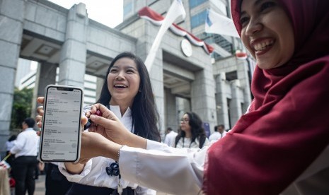 Pegawai Bank Indonesia (BI) menunjukkan bukti transaksi menggunakan peluncuran QR Code Indonesian Standard (QRIS) di halaman Gedung Bank Indonesia, Jakarta, Sabtu (17/8/2019).