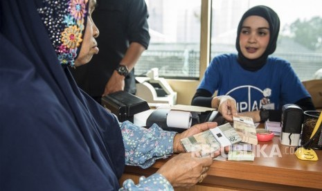 Pegawai bank melayani warga yang menukarkan uang (ilustrasi)