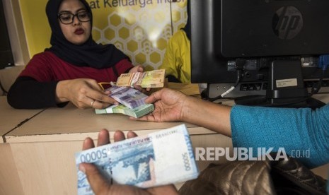 Pegawai bank melayani warga yang menukarkan uang