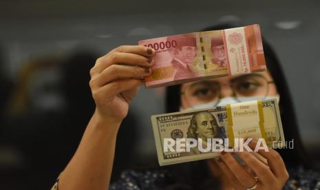 Pegawai menunjukkan mata uang rupiah dan dolar AS di salah satu gerai penukaran mata uang. ilustrasi