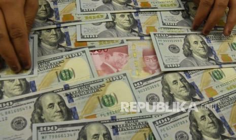 Pegawai menunjukkan mata uang rupiah dan dolar AS di salah satu gerai penukaran mata uang asing (ilustrasi). 