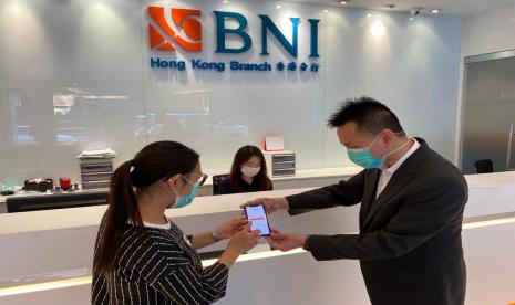 Pegawai sedang membantu nasabah untuk melakukan aktivasi BNI Mobile Banking di Kantor Cabang BNI Hongkong.