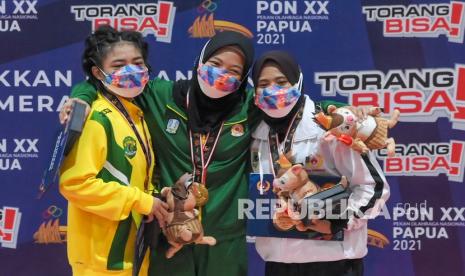 Pegulat putri Jatim Shinta Eka (tengah) berfoto bersama pegulat putri Kaltim Anissa Safitria (kiri) dan pegulat putri Sumbar Elvi Siska (kanan) usai penyerahan medali pertandingan Gulat Gaya Bebas kelas 50 Kg Putri PON Papua di GOR Futsal Dispora, Kabupaten Merauke, Papua, Jumat (8/10/2021). Shinta Eka meraih medali emas dan Anissa Safitria meraih medali perak sedangkan Elvi Siska meraih medali perunggu.