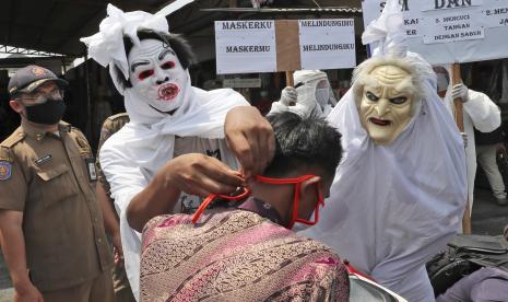 Petugas Satpol PP Kecamatan Larangan mensosialisasikan penggunaan masker dengan menggunakan kostum hantu pocong di Pasar Kreo, Kota Tangerang, Banten, Rabu (16/9/2020).