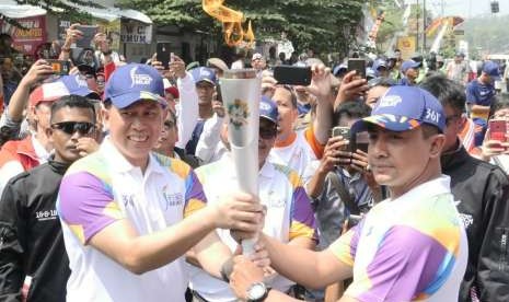 Pejabat sementara (PJs) Bupati Purwakarta, Muhammad Taufik Budi Santoso (kiri) menyerahkan obor Asian Games 2018, kepada Kapolres Purwakarta AKBP Twedi Aditya Benyhadi yang menjadi pelari pertama Torch relay Asian games 2018 di Purwakarta, Jumat (10/8). 