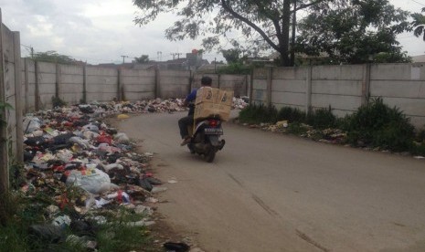 Pejalan kaki dan pengendapan motor melewati sampah yang menumpuk di jalur masuk Terminal Baleendah, Selasa (1/2).