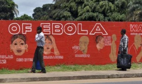 Pejalan kaki melewati mural yang memperlihatkan gejala ebola di Monrovia, Liberia.