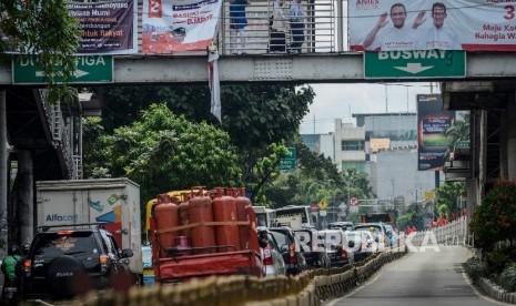 Pejalan kaki melintas di Jembatan Penyeberangan Orang (JPO) yang dipasangi alat peraga kampanye yang telah rusak di Duren Tiga, Jakarta Selatan, Jumat (9/12). 