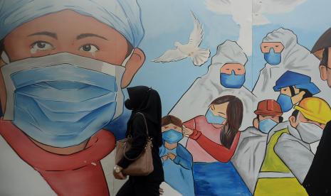 Pejalan kaki melintas didekat mural bertema covid-19 dikawasan Lapangan Bhayangkara, Jakarta.