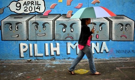  Pejalan kaki melintas disamping dinding yang bergambar kotak suara di kawasan Stasiun Cikini, Jakarta Pusat, Selasa (1/4).  (Republika/Agung Supriyanto)