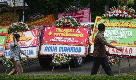 Pejalan kaki melintas disamping karangan bunga ucapan untuk keberhasilan pasangan Capres Cawapres Prabowo-Hatta di rumah Kertanegara, Jakarta, Jumat (11/7). 