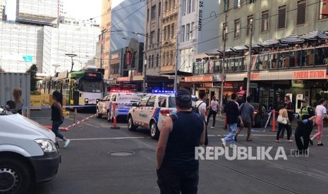  Pejalan kaki melintas saat polisi tiba di lokasi kejadian kendaraan yang menabrak pejalan kaki di Melbourne, Kamis (21/12). 