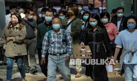 Pejalan kaki memakai masker saat melintasi persimpangan di Hong Kong. emerintah Hong Kong mengatakan populasinya telah menyusut untuk tahun kedua. Ilustrasi.