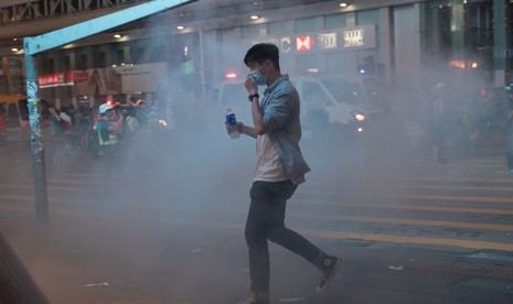 Pejalan kaki terperangkap dalam awan gas air mata yang ditembakkan oleh polisi anti-huru hara setelah demonstrasi menentang kebrutalan polisi dan untuk berdiri bersama Muslim dan wartawan di Hong Kong, Cina, 27 Oktober 2019. 