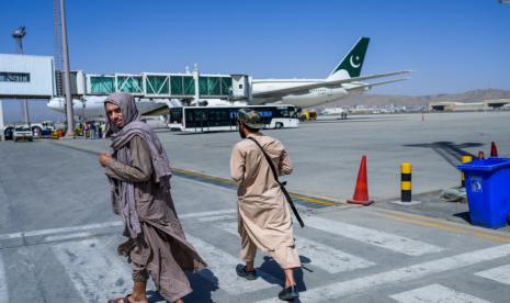 Krisis Ekonomi, Taliban Minta Bantuan Internasional . Foto: Pejuang Taliban berpatroli di seminar Bandara Kabul saat pesawat perdana asal Pakistan mendarat .