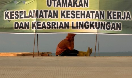 Pekerja beristirahat di dekat spanduk himbauan Keselamatan dan Kesehatan Kerja K3 di Makassar, Sulawesi Selatan, Jumat (2/11/2018).