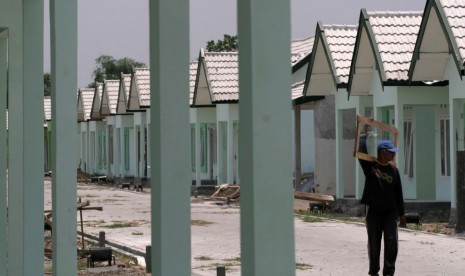 Pekerja berjalan di kompleks rumah sederhana untuk masyarakat kelas bawah.