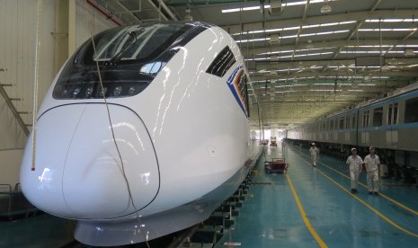 Pekerja berjalan di samping kereta cepat di pabrik kereta CRRC Guangdong, Jiangmen, Cina, Jumat (3/11). 