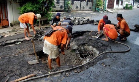 Pekerja dari Suku Dinas Tata Air Jakarta Timur memperbaiiki jalan yang amblas di Jalan Cipinang Cempedak IV, Jakarta Timur, Senin (16/6). 