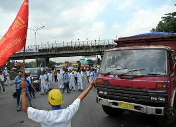 Pekerja demonstrasi melakukan aksi blokir jalan tol Jakarta-Cikampek, Cibitung, Jawa Barat, Jumat (27/1).  (Republika/Tahta Aidilla)