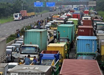 Pekerja demonstrasi melakukan aksi blokir jalan tol Jakarta-Cikampek, Cibitung, Jawa Barat, Jumat (27/1).  (Republika/Tahta Aidilla)