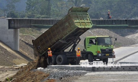 Pekerja dengan menggunakan alat berat mengurug bahu jalan di lokasi proyek Jalan Tol Serang - Panimbang. ilustrasi