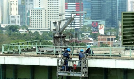 Pekerja dengan perlengkapan keselamatan kerja membersihkan dinding gedung bertingkat di Jakarta, Rabu (29/7). 