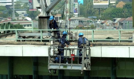 Pekerja dengan perlengkapan keselamatan kerja membersihkan dinding gedung bertingkat di Jakarta, Rabu (29/7). 