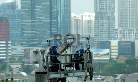 Pekerja dengan perlengkapan keselamatan kerja membersihkan dinding gedung bertingkat di Jakarta, Rabu (29/7). 