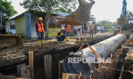 Pekerja dibantu alat berat menyelesaikan pemasangan pipa induk distribusi air bersih (ilustrasi)