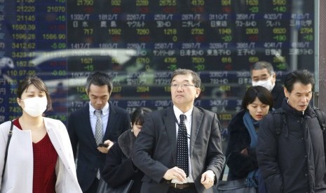 Pekerja Jepang melintas di depan monitor pergerakan harga saham milik sebuah perusahaan sekuritas. Ekonomi Jepang mengalami rebound 1,4 persen.