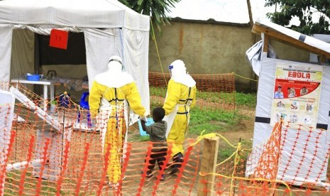 Pekerja medis menggandeng seorang anak laki-laki yang terpapar virus ebola di pusat rehabilitasi ebola di Beni, Kongo Timur. 