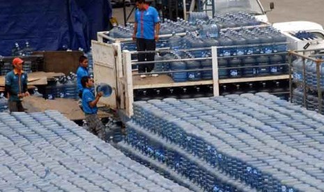 Pekerja melakukan bongkar muat air minum dalam kemasan di depot penyimpanan.