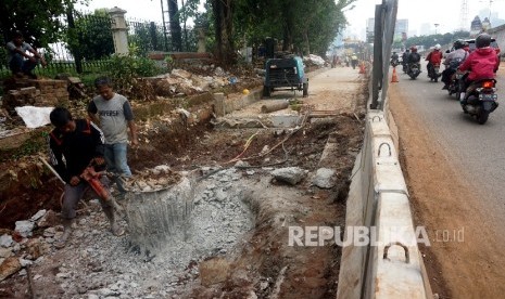 Pekerja melakukan pelebaran jalan di kawasan perempatan Pancoran, Jakarta.