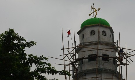 Pekerja melakukan pengecetan sebuah menara masjid yang berlambang panah beserta busur panahnya di Kebayoran Lama, Jakarta, Jumat (11/3).