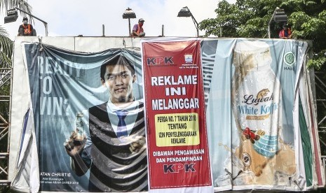 Pekerja melepaskan reklame yang melanggar izin di jalan POM IX Palembang, Sumatera Selatan, Kamis (6/12/18). 