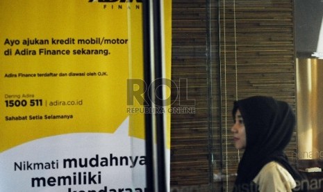  Pekerja melintas berlatar belakang penyaluran kredit Adira Finance di Jakarta, Jumat (21/8). 