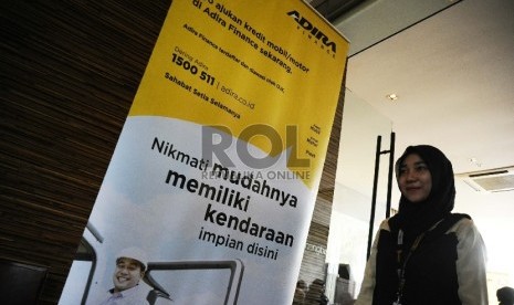  Pekerja melintas berlatar belakang penyaluran kredit Adira Finance di Jakarta, Jumat (21/8). 