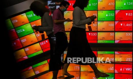 Pekerja melintas dengan latar belakang layar pergerakan harga saham di Bursa Efek Indonesia, Jakarta, Jumat (30/4). Sepanjang kuartal I 2021, kapitalisasi 20 emiten BUMN mengalami penurunan 1,3 persen