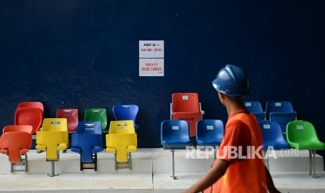 Pekerja melintas di dekat contoh bangku yang akan digunakan untuk tribun Stadion Utama Gelora Bung Karno (GBK), Jakarta, Selasa (18/10).