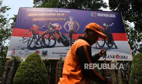 Pekerja melintas di depan baliho sosialisasi Asian Para Games 2018 di Jakarta Selatan, Selasa (24/9).