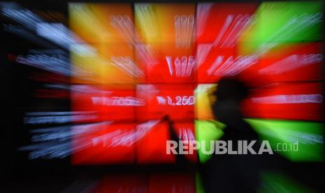 Pekerja melintas di depan layar indeks harga saham di Bursa Efek Indonesia, Jakarta. Republika mencatat meski IHSG memerah namun saham energi dan tambah masih menguat