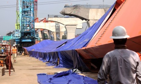 Pekerja melintas di samping Steel I Girder (SIG) proyek jalan tol layang Jakarta-Cikampek yang membentang hingga sisi jalan, di Cikarang km 28 arah Cikampek, Kabupaten Bekasi, Jawa Barat, Rabu (22/5/2019).